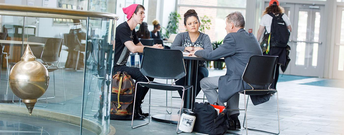 a professor sits and has a conversation with two Frostburg students in the Gira Center